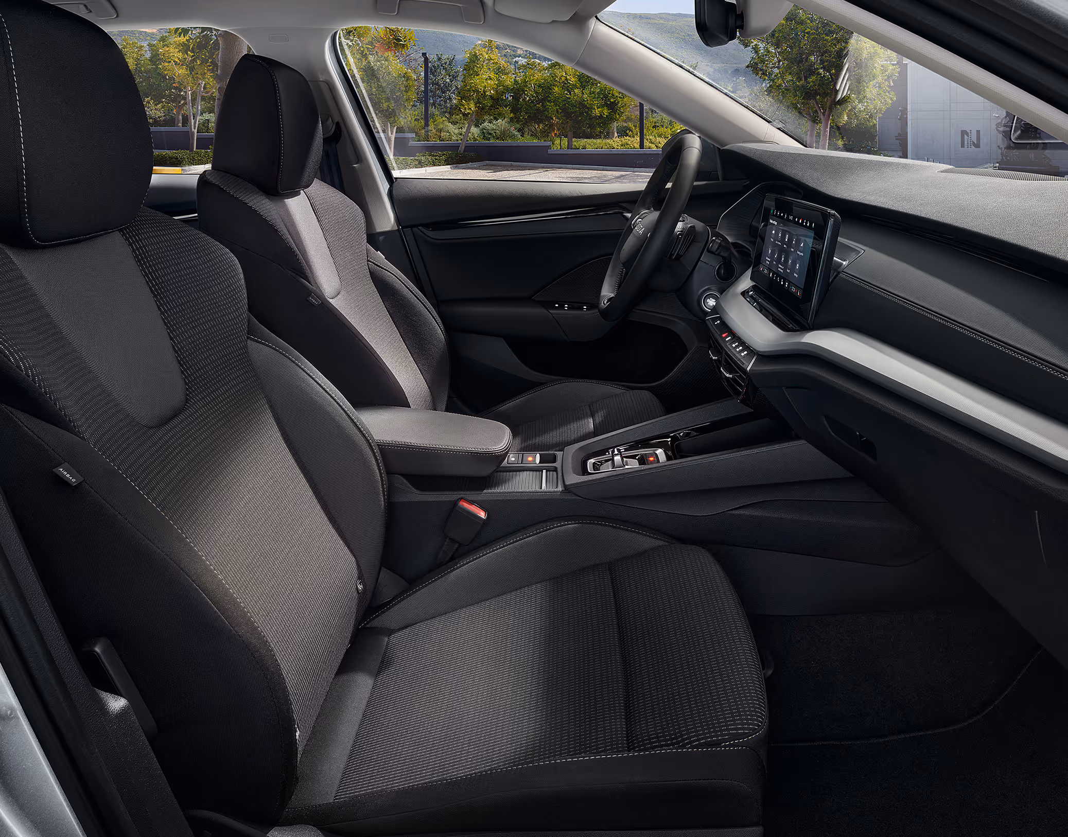 Beifahrer-Perspektive im Innenraum des Škoda Elroq in der Ausstattungslinie “Loft”. Der Blick fällt auf das Lenkrad, das Digital Cockpit und den zentralen Infotainment-Bildschirm.