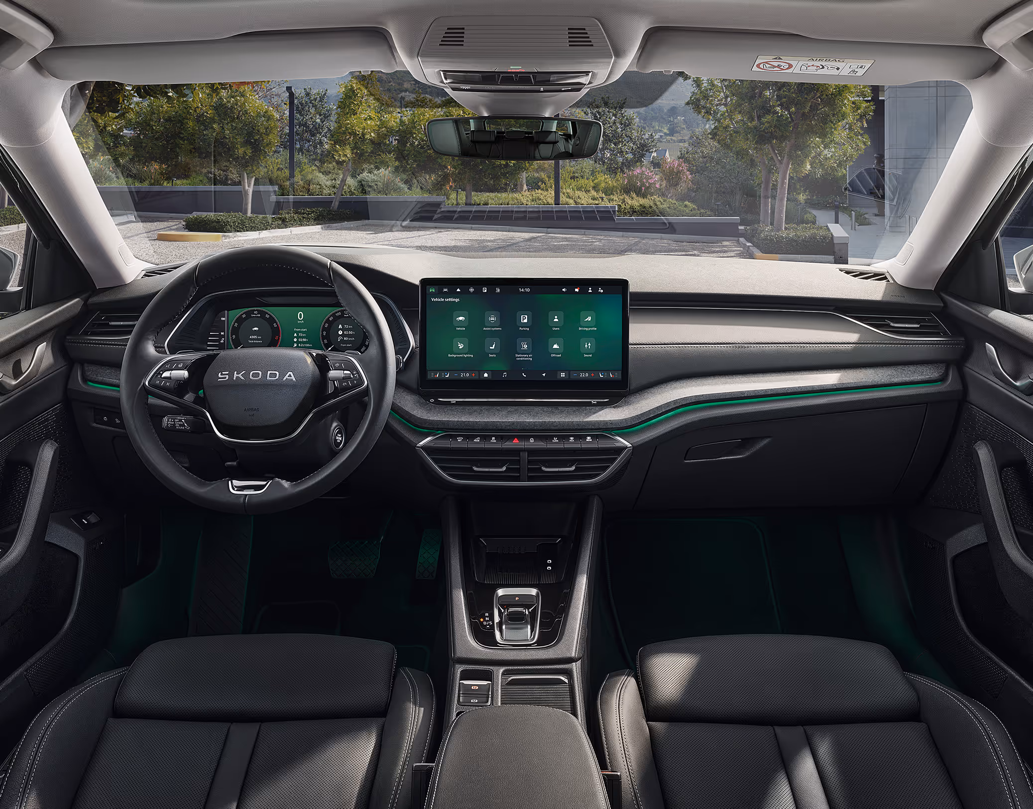 Blick über die Mittelarmlehne auf das Lenkrad, das Infotainmentsystem und das Armaturenbrett im Škoda Elroq. Türkise Ambient-Beleuchtung.