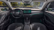 Eine weite Innenansicht zeigt das gesamte Cockpit eines Škoda Octavia mit der Design Selection Lodge. Das Interieur ist mit einer Wollstoff-Kunstleder-Kombination mit gelben Kontrastnähten und einer Dekorleiste in Silber-Grau am Armaturenbrett ausgestattet. Durch die Windschutzscheibe ist eine begrünte, städtische Umgebung zu sehen.