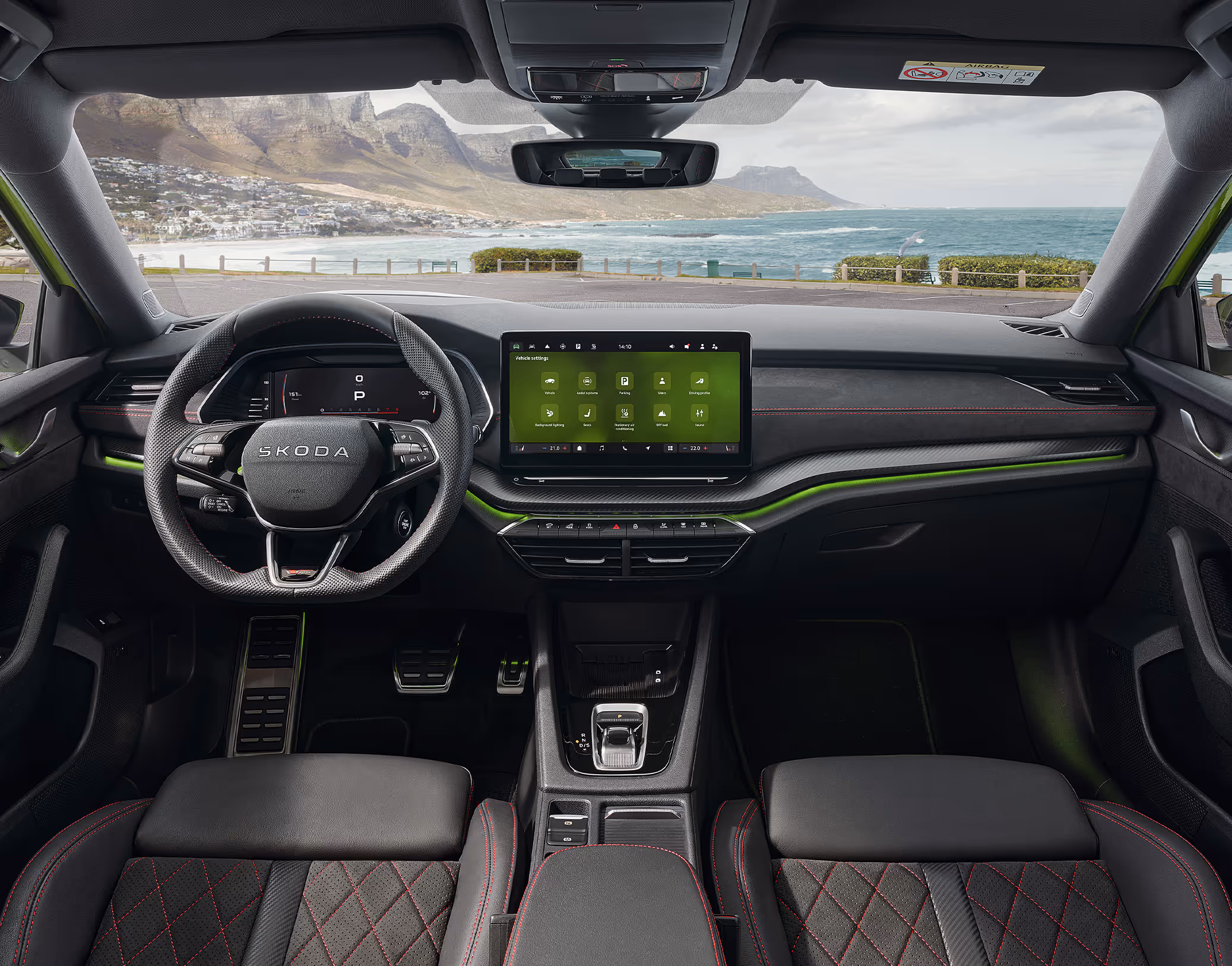 Blick über die Mittelarmlehne auf das Lenkrad, das Infotainmentsystem und das Armaturenbrett im Škoda Elroq in der Ausstattungslinie “Lodge”.