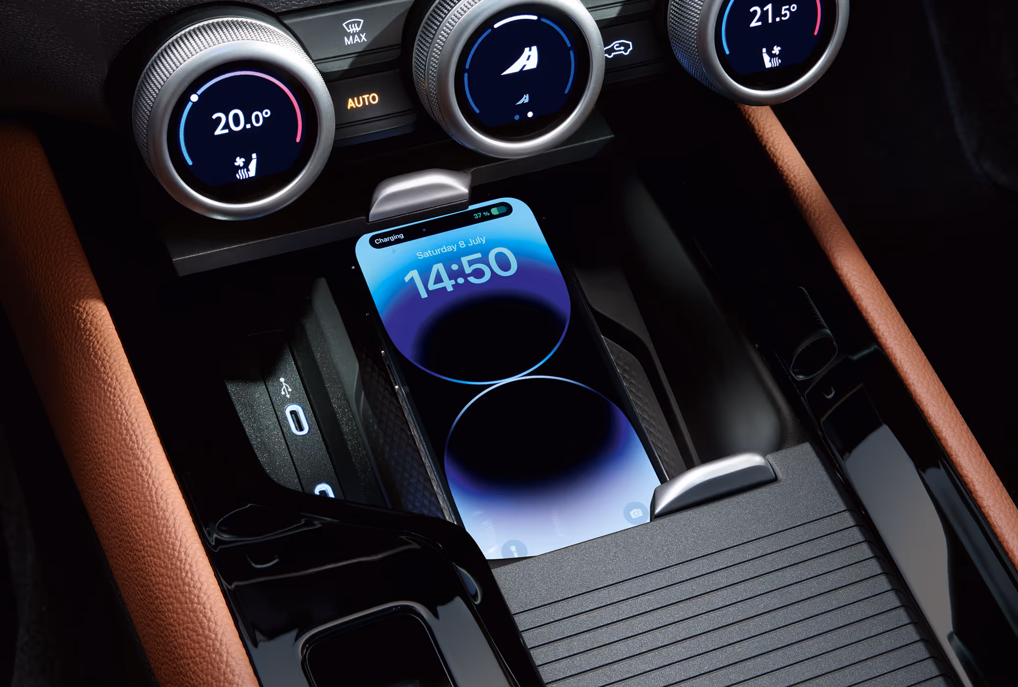 Eine Nahaufnahme zeigt die Phonebox in der Mittelkonsole eines Škoda Superb, in der ein Smartphone kabellos geladen wird. Auf dem Bildschirm des Telefons wird der Ladevorgang und die Uhrzeit 14:50 angezeigt. Direkt über der Ladeschale befinden sich die drei multifunktionalen Smart Dials zur Steuerung der Klimaanlage.