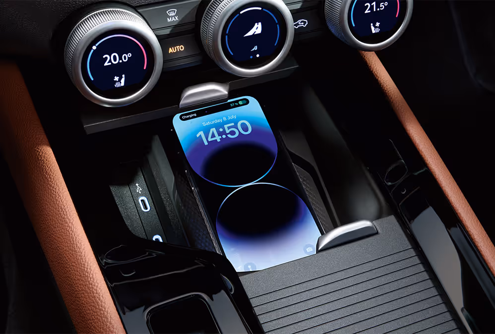 Eine Nahaufnahme zeigt die Phonebox in der Mittelkonsole eines Škoda Superb, in der ein Smartphone kabellos geladen wird. Auf dem Bildschirm des Telefons wird der Ladevorgang und die Uhrzeit 14:50 angezeigt. Direkt über der Ladeschale befinden sich die drei multifunktionalen Smart Dials zur Steuerung der Klimaanlage.