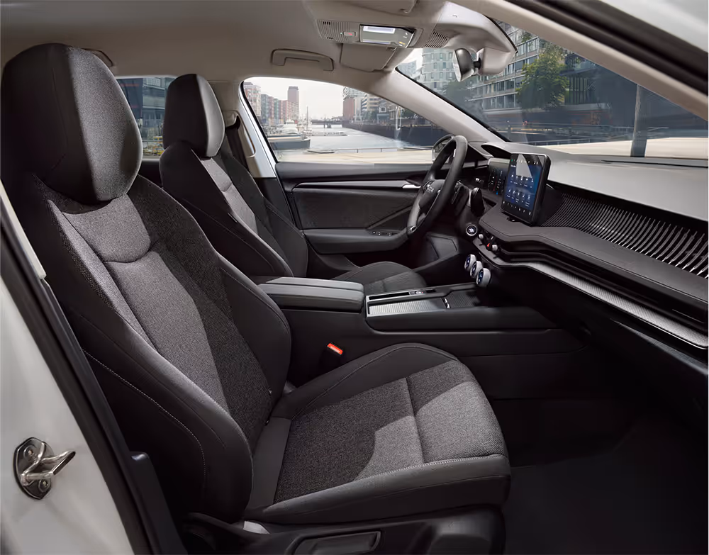 Beifahrer-Perspektive im Innenraum des Škoda Elroq in der Ausstattungslinie “Studio”. Der Blick fällt auf das Lenkrad, das Digital Cockpit und den zentralen Infotainment-Bildschirm.