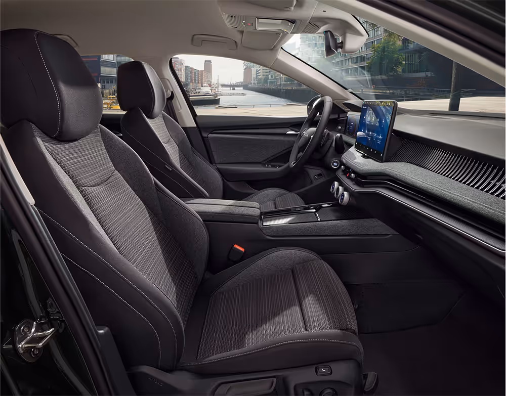 Beifahrer-Perspektive im Innenraum des Škoda Elroq in der Ausstattungslinie “Loft”. Der Blick fällt auf das Lenkrad, das Digital Cockpit und den zentralen Infotainment-Bildschirm.