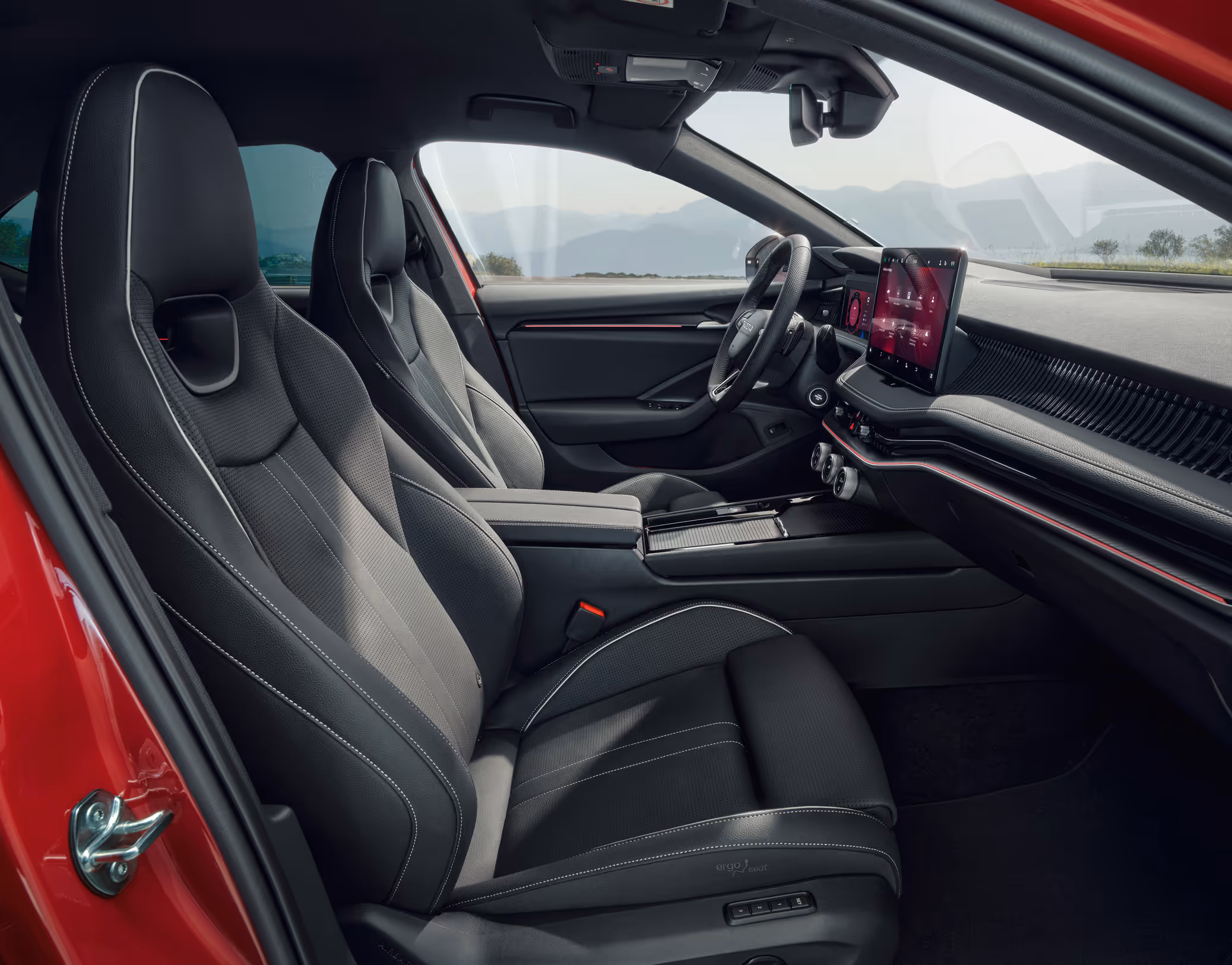 Eine seitliche Innenansicht des Škoda Superb zeigt das sportliche Interieur der Design Selection Suite Sportline. Die schwarzen Sportsitze mit integrierten Kopfstützen sind mit einer Leder-Kunstleder-Kombination bezogen und werden durch graue Kontrastnähte akzentuiert. Durch die Fenster ist eine bergige Küstenlandschaft sichtbar.