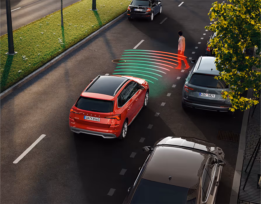 Animation des Frontrad- und Ausweichassistenten. Der rote Škoda Kamiq fährt die Straße entlang. Plötzlich überquert ein Fußgänger, der aus einem schwer einsehbaren Bereich kommt, die Straße. Das System warnt.