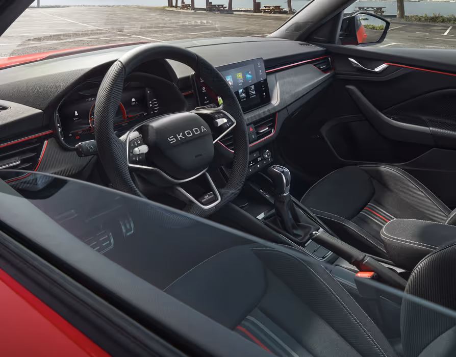 Ein Mann im Fahrersitz interagiert mit der Person auf dem Beifahrersitz. Auf dem Infotainment-Display sind die Icons verschiedener Smartphone-Apps zu sehen, was die SmartLink-Konnektivität ausdrücken soll.