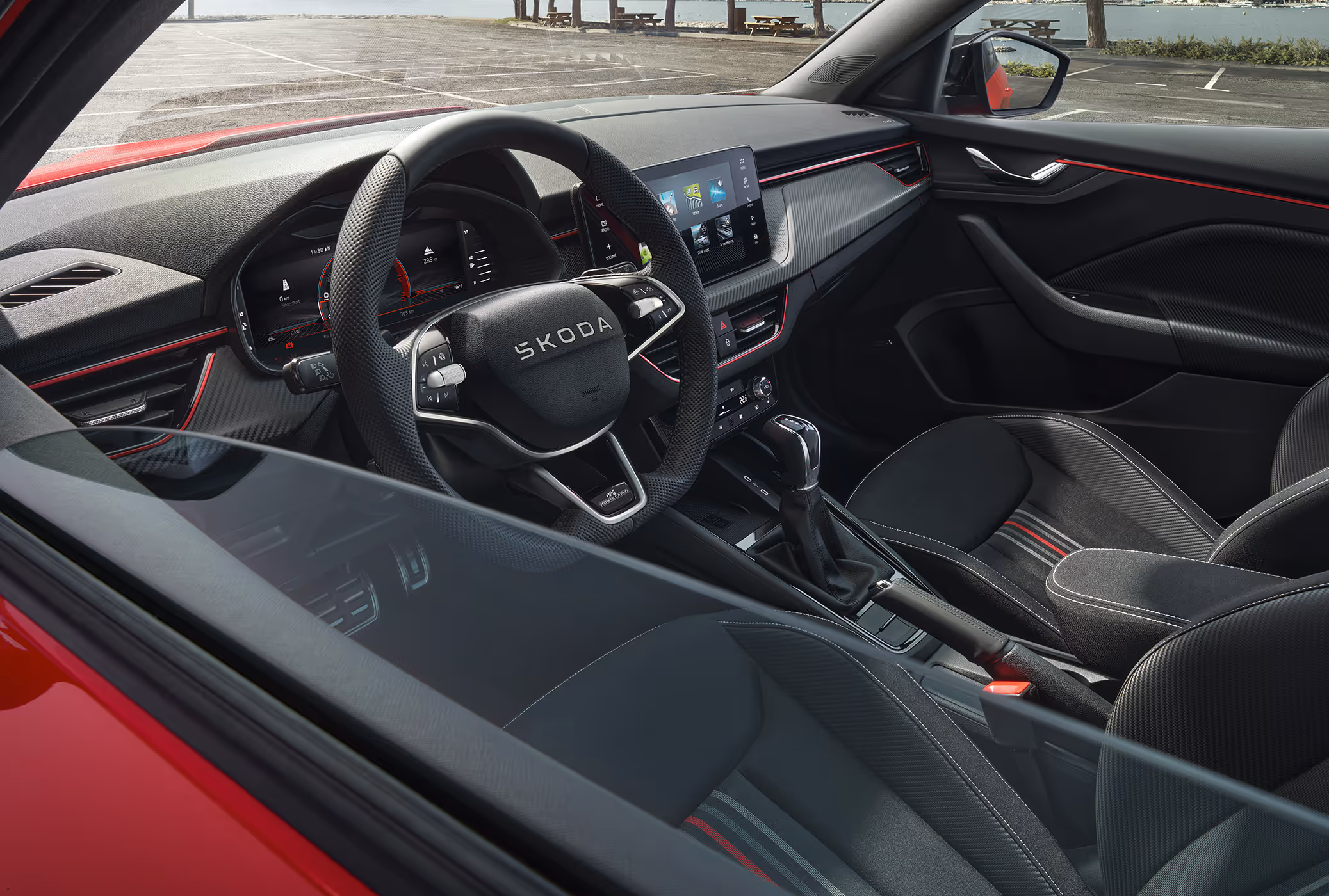 Ein Mann im Fahrersitz interagiert mit der Person auf dem Beifahrersitz. Auf dem Infotainment-Display sind die Icons verschiedener Smartphone-Apps zu sehen, was die SmartLink-Konnektivität ausdrücken soll.