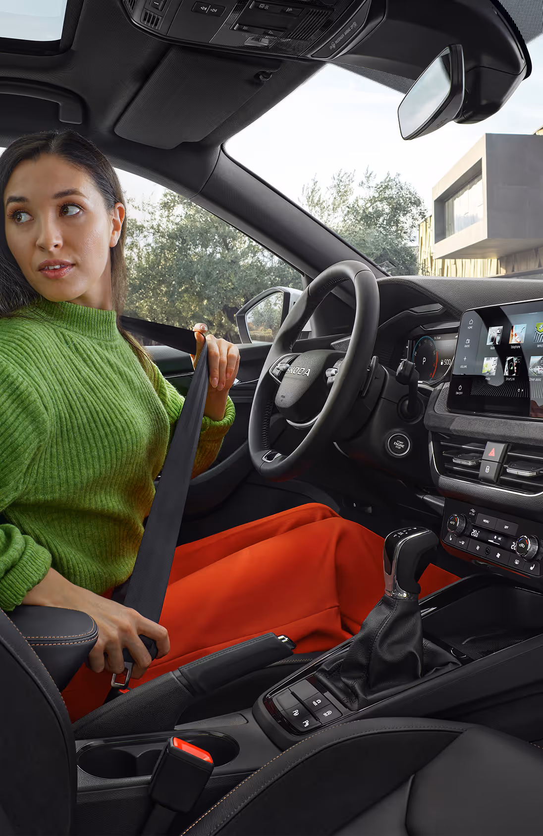 Das Cockpit des Škoda Elroq mit Blick auf das Lenkrad und den freistehenden 13-Zoll-Infotainmentbildschirm. Die grüne Ambientebeleuchtung setzt einen farbigen Akzent entlang des Armaturenbretts und der Türen.