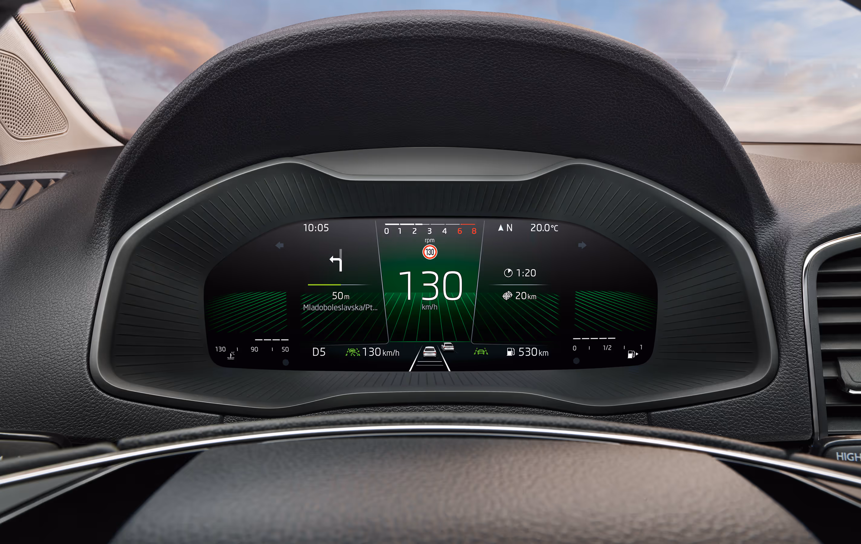 Eine Nahaufnahme des Digitalen Cockpits in einem Škoda Karoq zeigt eine Vielzahl von Fahrinformationen in einer spezifischen Layout-Ansicht. Im Zentrum stehen die digitale Geschwindigkeitsanzeige von 130 km/h und Navigationsanweisungen, umgeben von Daten wie Reichweite, Uhrzeit und aktiven Assistenzsystemen.