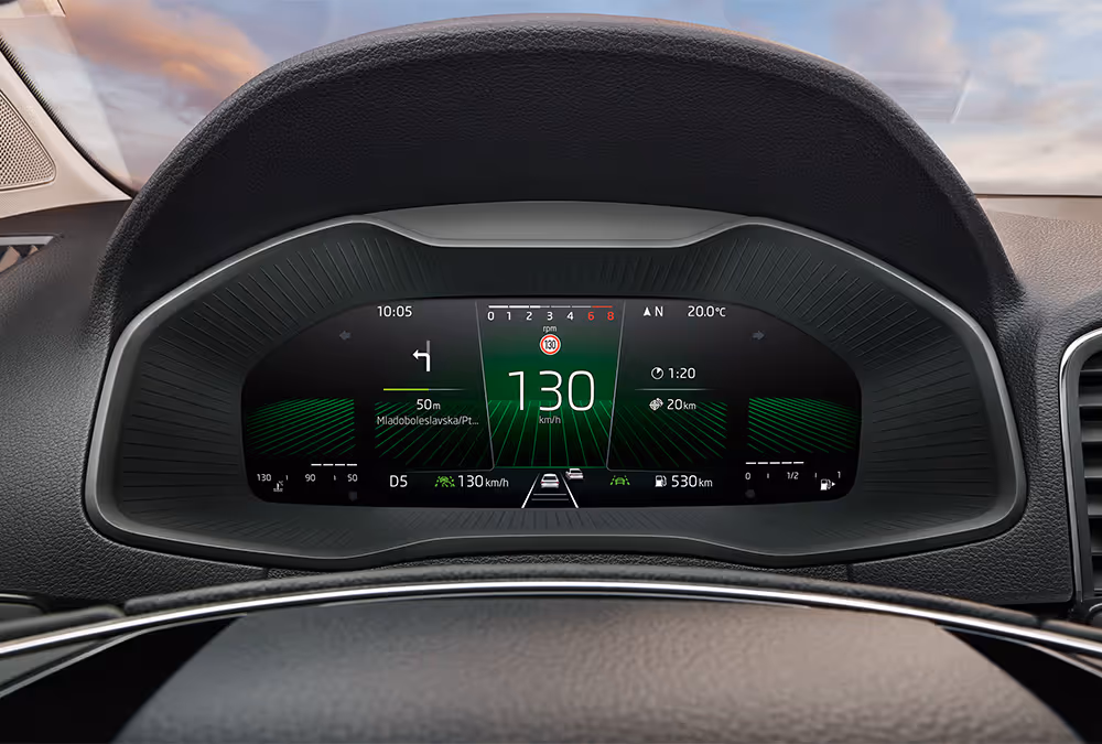 Eine Nahaufnahme des Digitalen Cockpits in einem Škoda Karoq zeigt eine Vielzahl von Fahrinformationen in einer spezifischen Layout-Ansicht. Im Zentrum stehen die digitale Geschwindigkeitsanzeige von 130 km/h und Navigationsanweisungen, umgeben von Daten wie Reichweite, Uhrzeit und aktiven Assistenzsystemen.