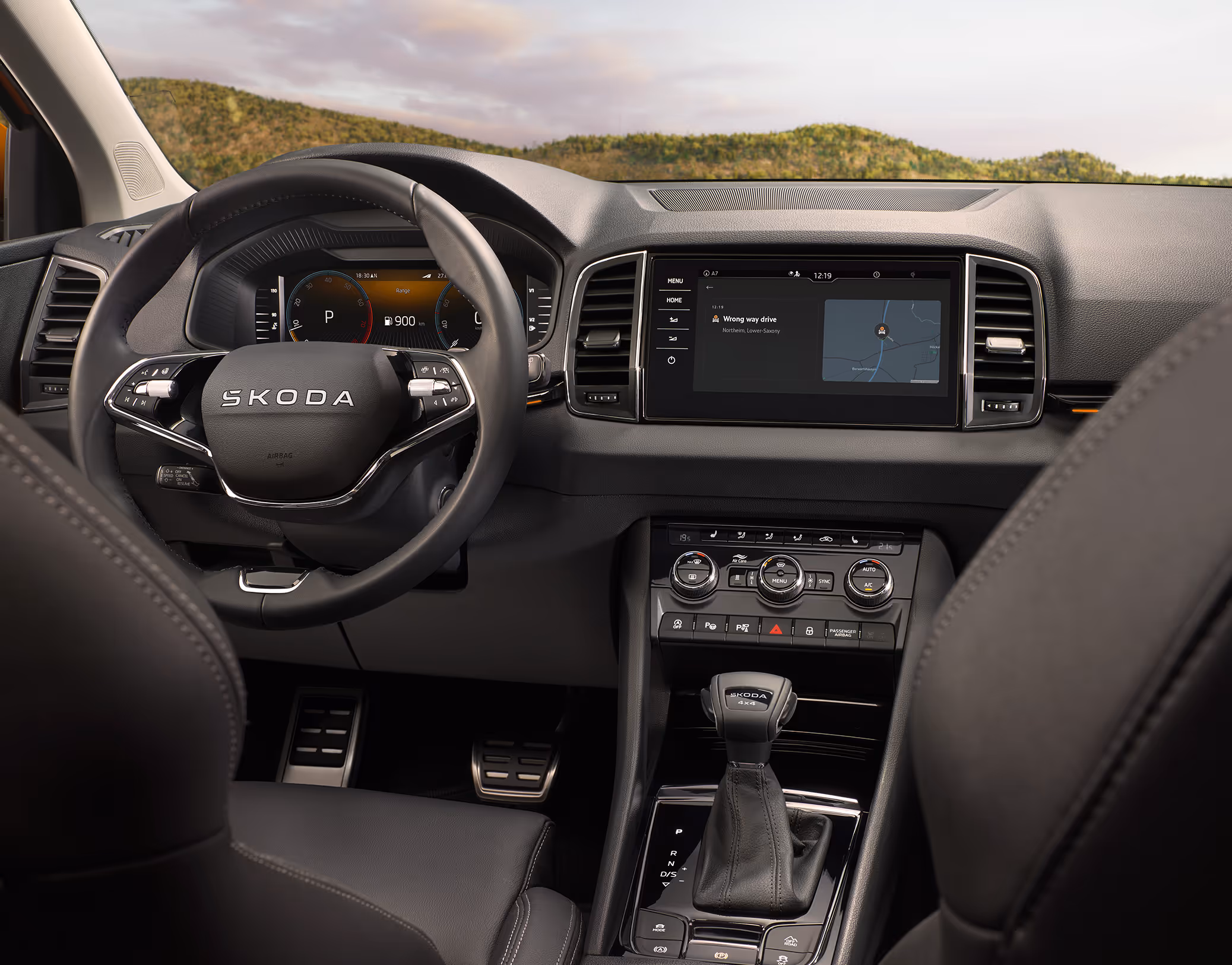 Eine Ansicht aus dem Cockpit eines Škoda Karoq zeigt das Armaturenbrett, das digitale Cockpit und das zentrale Infotainment-Display. Auf dem Display ist eine Informations- und Kartenansicht zu sehen.