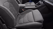 Eine Nahaufnahme zeigt den Beifahrersitz eines Škoda Kodiaq mit der Design Selection Loft. Der Sitz ist mit einem grauen Stoff bezogen, der ein markantes Steppmuster aufweist, und wird durch Kontrastnähte in Zitrusgelb an den dunkleren Seitenwangen akzentuiert. Im Hintergrund sind die Mittelarmlehne und der Fahrersitz zu sehen.