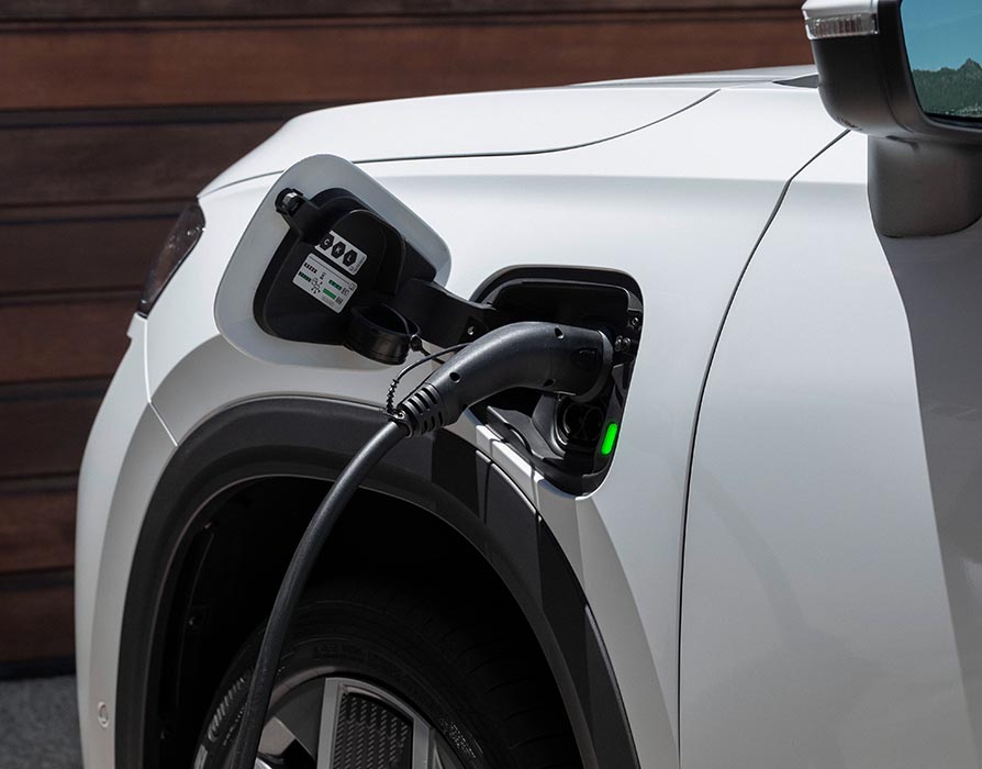 Eine Nahaufnahme zeigt die Phonebox in der Mittelkonsole eines Škoda Kodiaq, in der zwei Smartphones nebeneinander kabellos geladen werden. Das Ablagefach befindet sich direkt unter den Smart Dials und ist von den cognac-braunen Lederelementen der Design Selection Lounge umgeben.