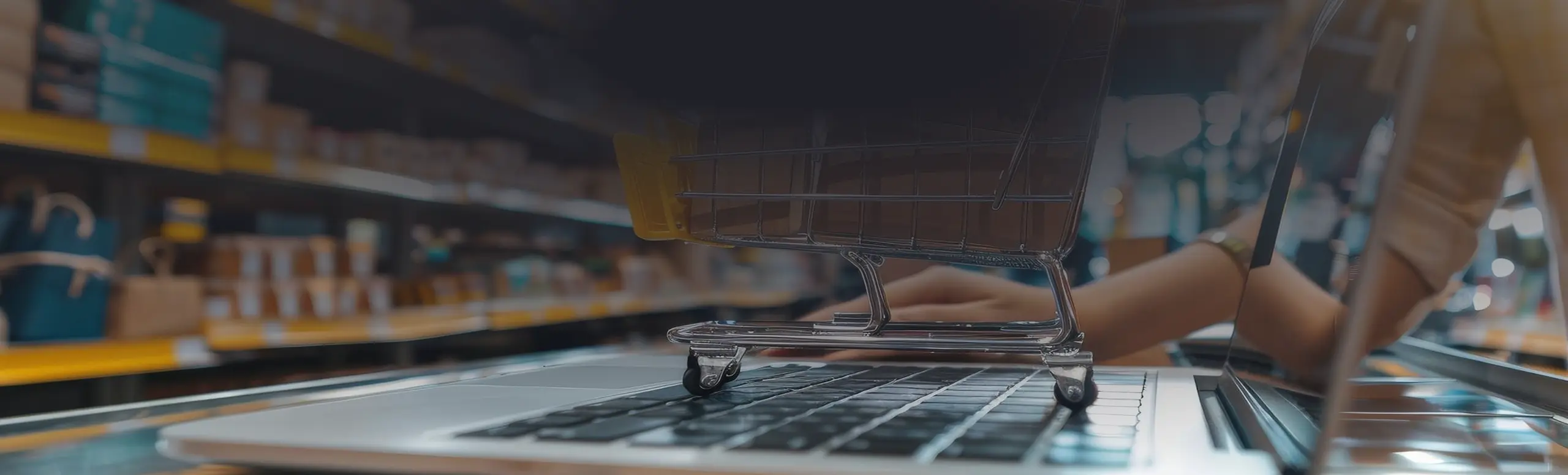 Small empty shopping cart on a laptop keyboard with blurred store shelves in the background.