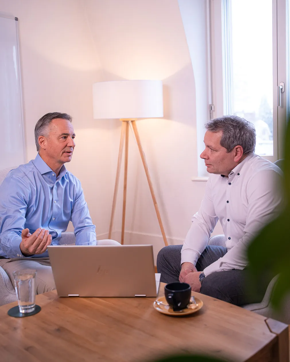 In einem Besprechungsraum sitzt Roman Wider und bespricht etwas mit einem Mann in einem weissen Hemd. Der Laptop steht aufgeklappt auf dem Tisch.
