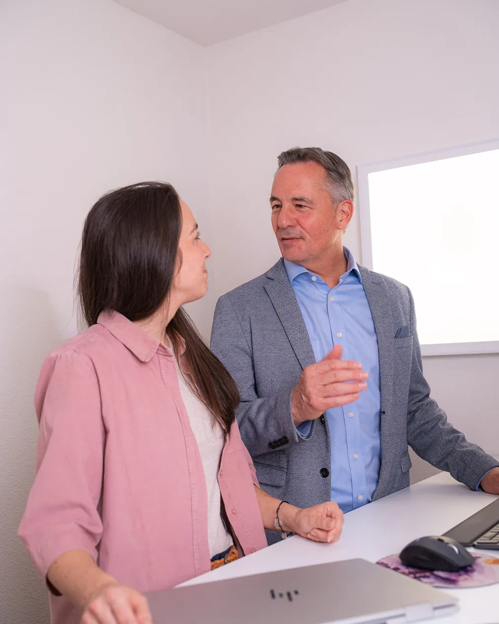 Carina Messmer und Roman Wider stehen an einem Schreibtisch und besprechen etwas.