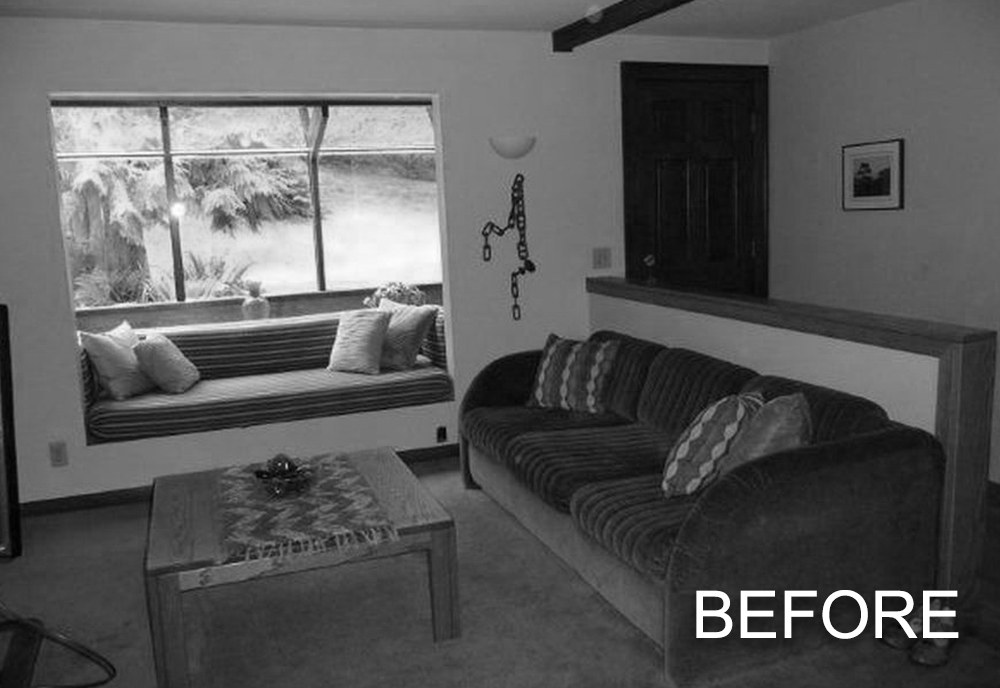 Living room with a striped couch, a wooden coffee table, and a window seat with cushions overlooking a garden.