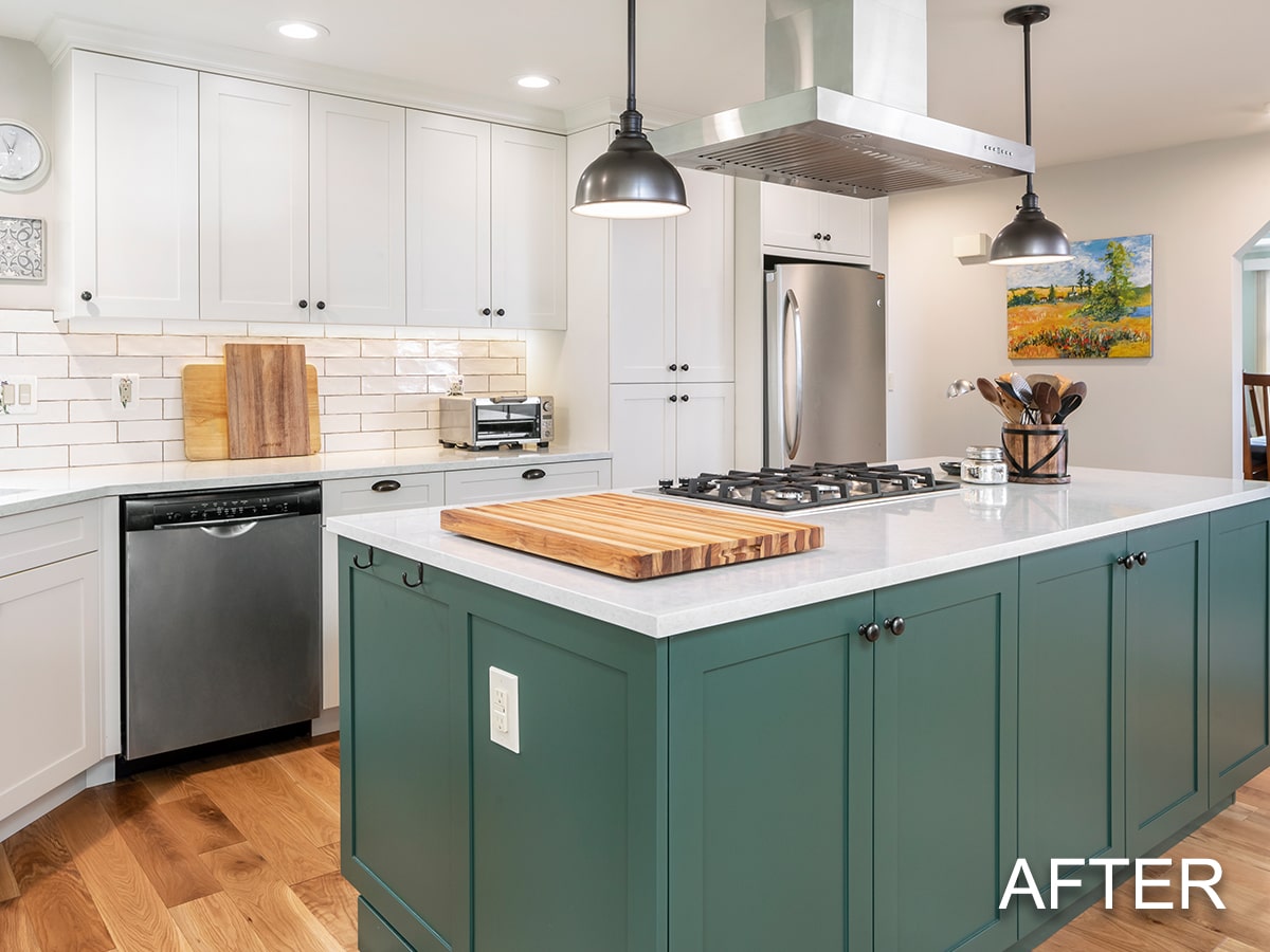 Modern kitchen with white upper cabinets, green island with white countertop, stainless steel appliances, and wooden cutting boards.