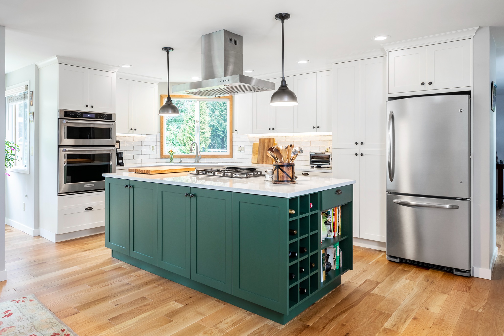 kitchen remodel with green island, white shaker cabinets, stainless appliances, and hardwood floors