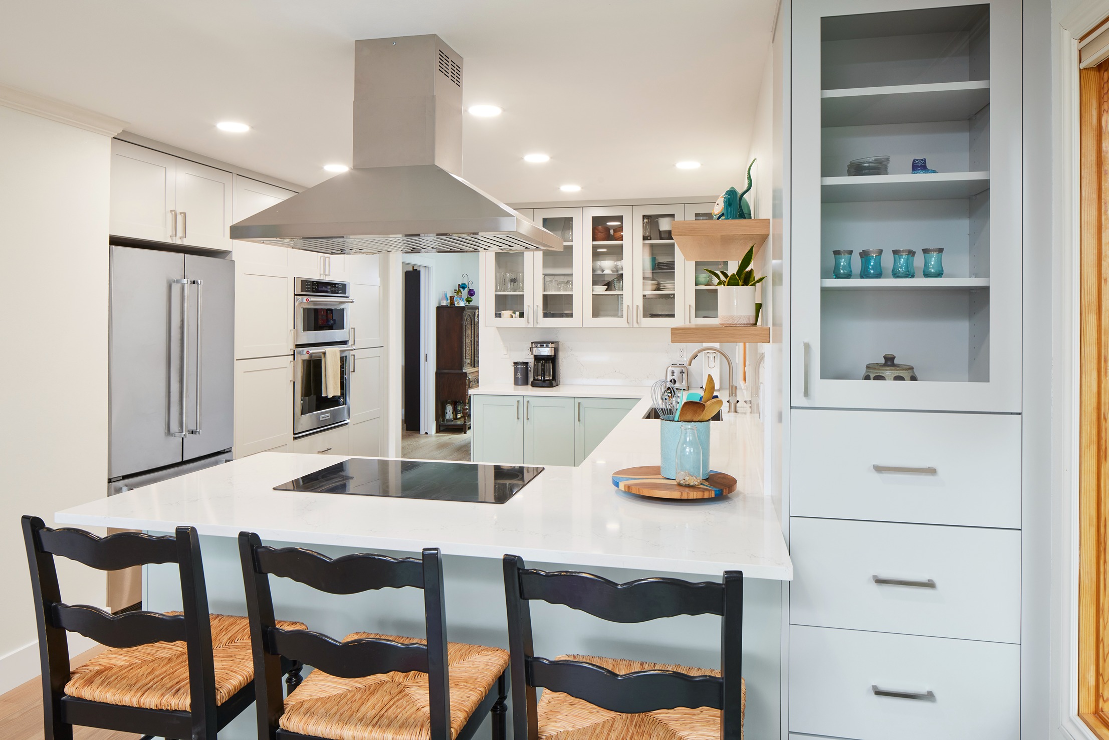 Modern kitchen renovation featuring white shaker cabinetry, quartz countertops, island cooktop, stainless appliances