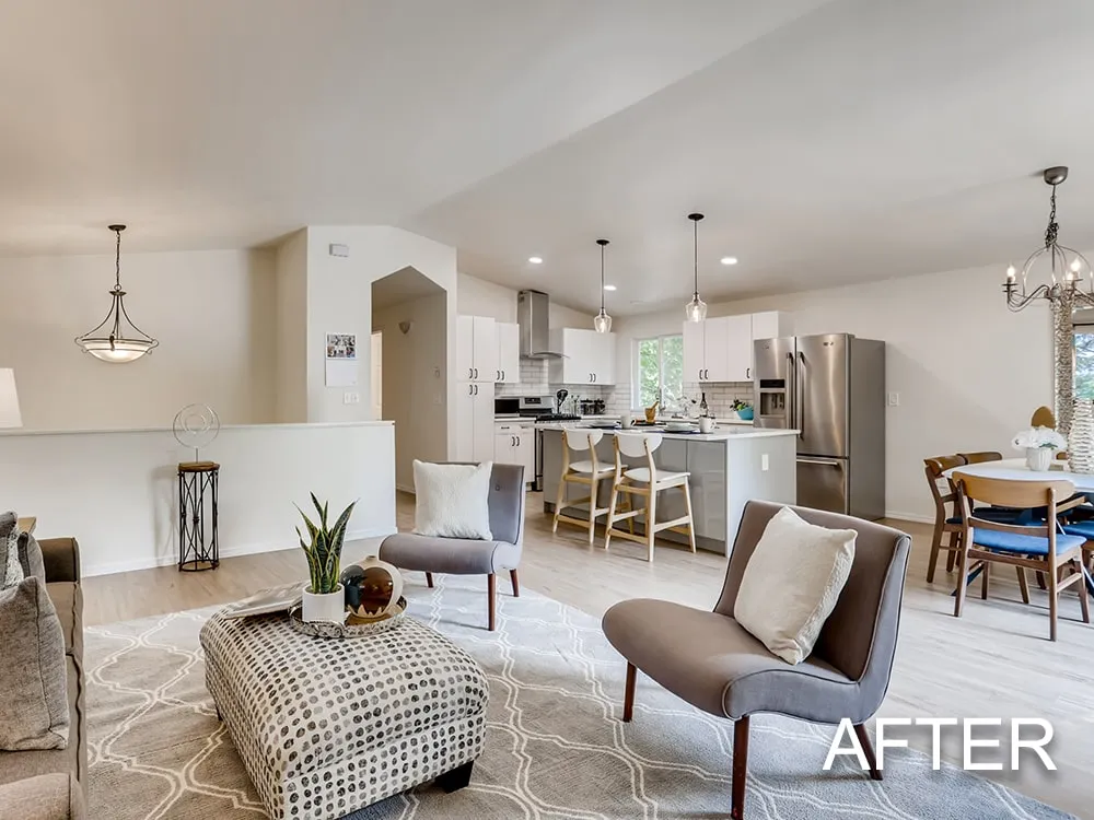 Bright modern living room with large sliding glass door, two brown accent chairs, patterned ottoman, and a dining area with wooden table and chairs.