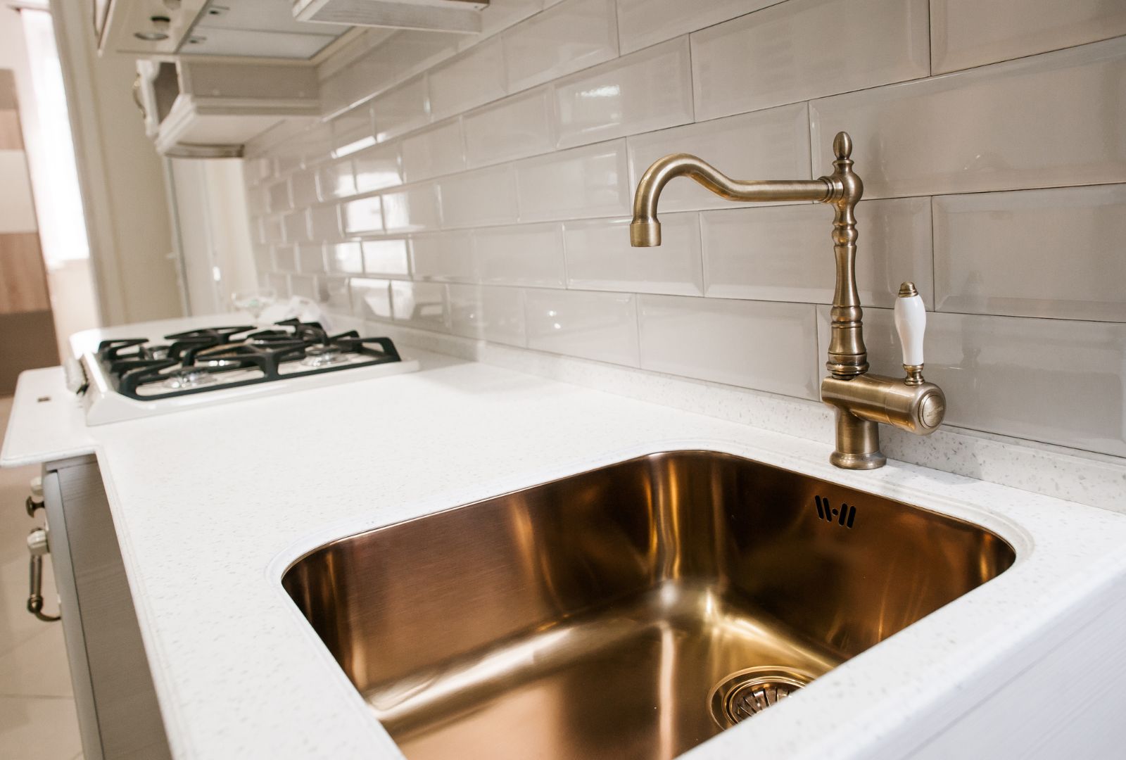 Angle view of kitchen sink with gold faucet