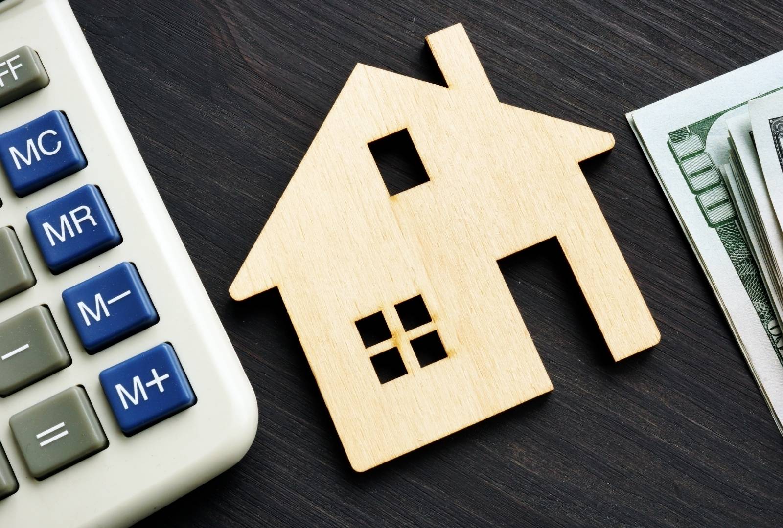 Home value. Wooden house with calculator and money.