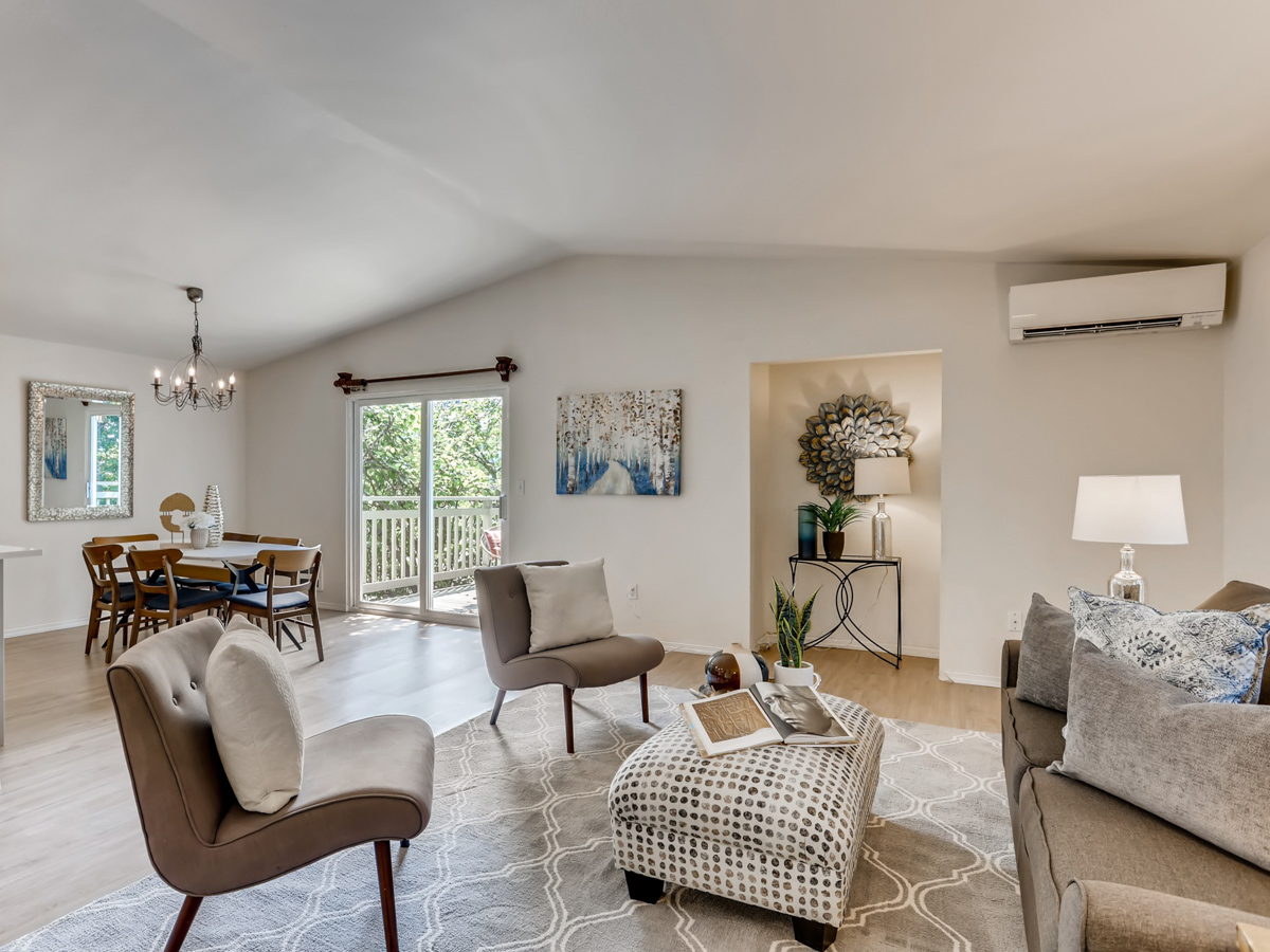 Open living and dining area in a modern coastal home remodel with soft neutral tones, wood flooring, and sliding glass doors that bring in natural light.