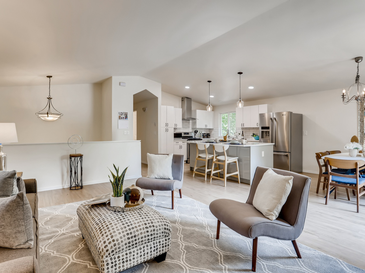 Open living and dining area in a modern coastal home remodel with soft neutral tones, wood flooring, and sliding glass doors that bring in natural light.