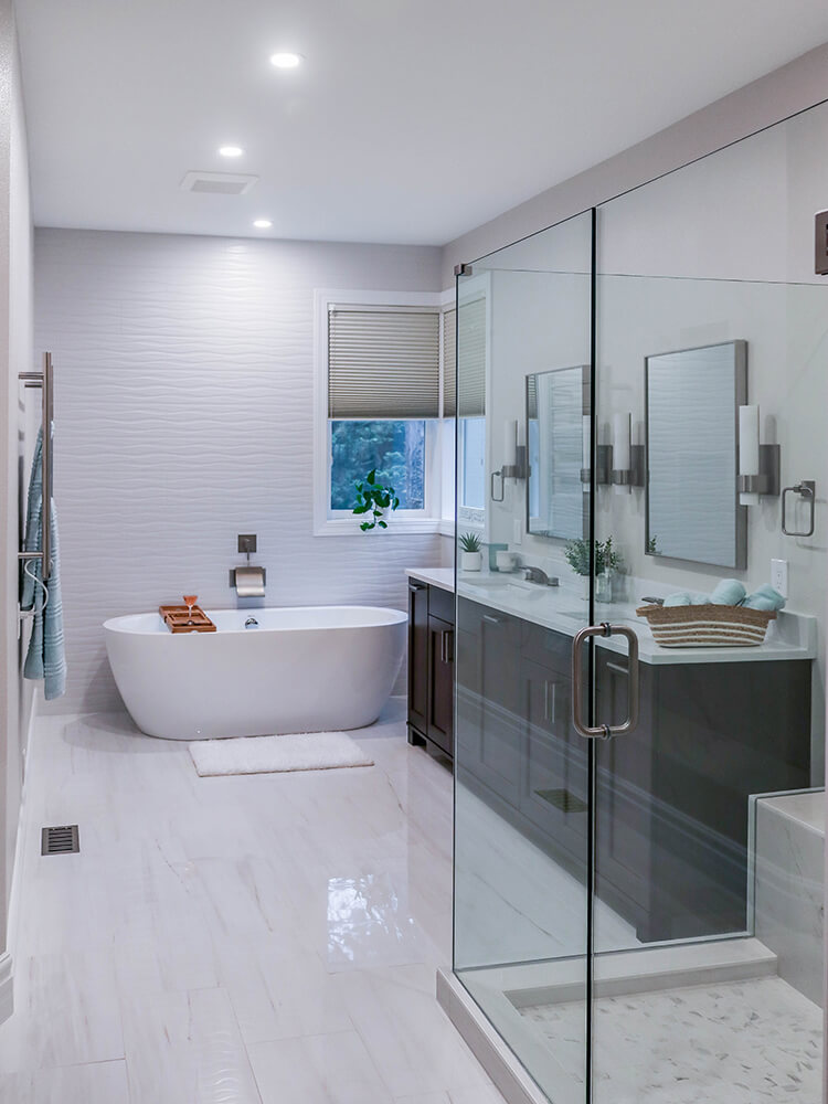 Luxury walk-in shower with glass enclosure and marble tile walls featuring built-in niches and brushed nickel fixtures in a contemporary bathroom design.