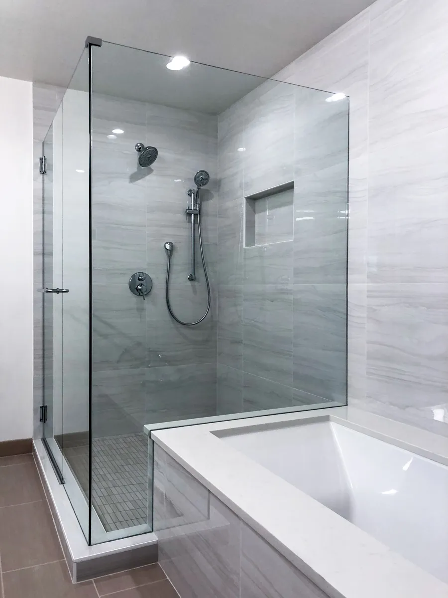 frameless shower enclosure bathroom with chrome finish hardware and fixtures and a built-in undermount tub