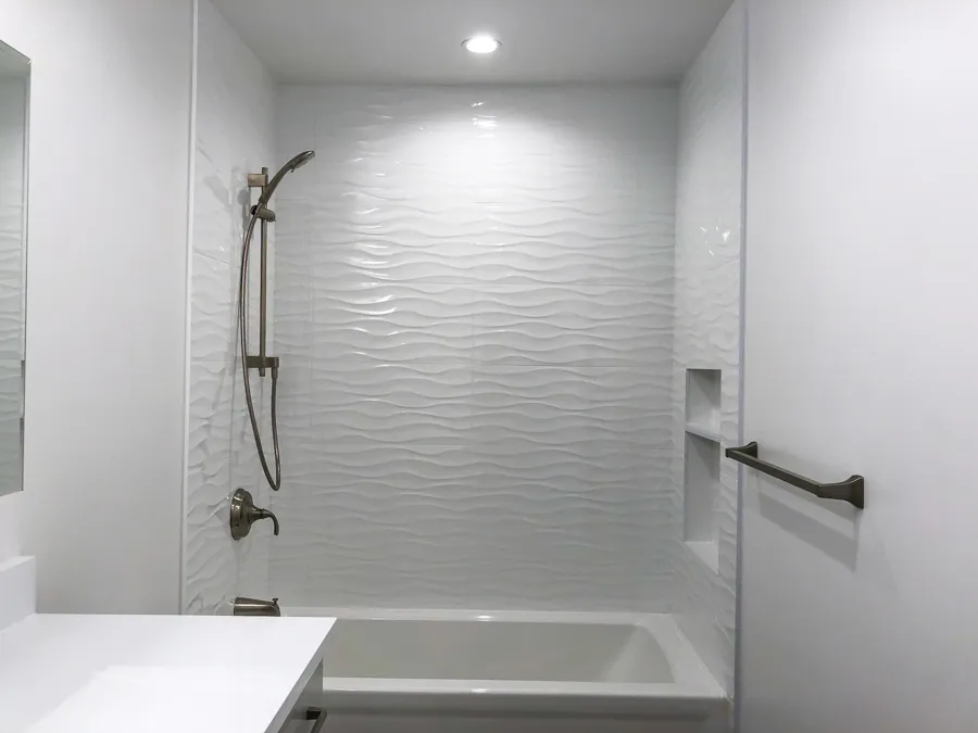 Walk-in shower featuring chrome rainfall showerhead, handheld sprayer, and large gray porcelain wall tiles.