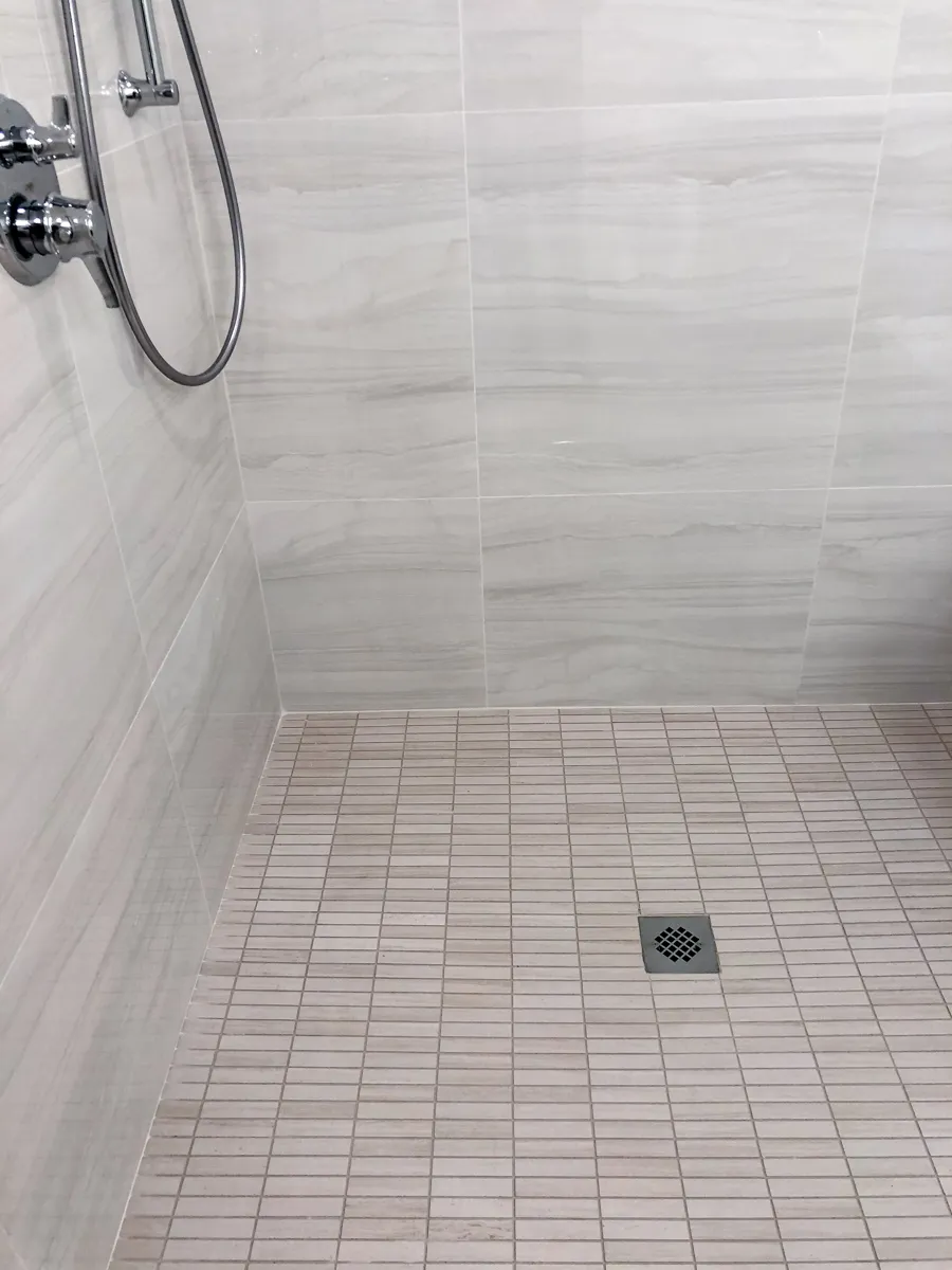 Double bathroom vanity with woodgrain cabinets, white quartz countertop, and large frameless mirror in a modern bathroom.