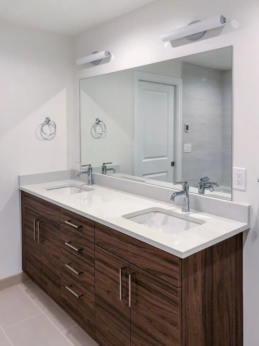 Contemporary double-sink vanity with sleek chrome faucets, white countertop, and minimalist lighting