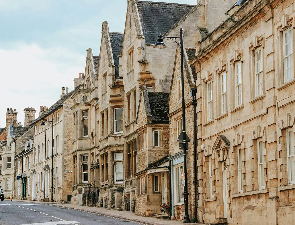 Historic stone buildings in Stamford under a cloudy sky.