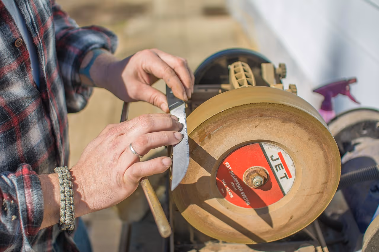 Eine Person, welche ein Messer an einer Schleifmaschine schärft - beschreibend für unseren Schärfdienst