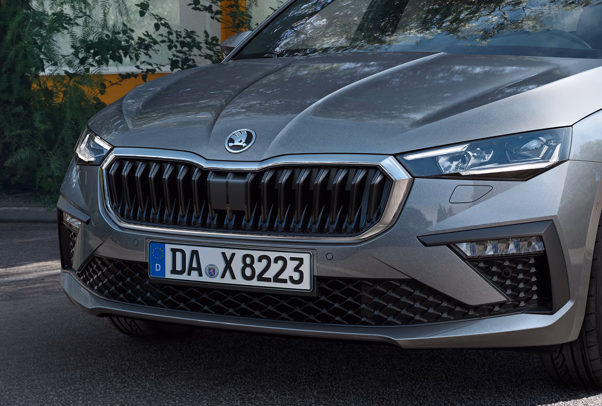 Eine Nahaufnahme zeigt die Frontpartie eines Škoda Scala in der Lackierung Graphite-Grau Metallic. Die Aufnahme hebt den markanten Kühlergrill und die TOP LED-Matrix-Scheinwerfer hervor.