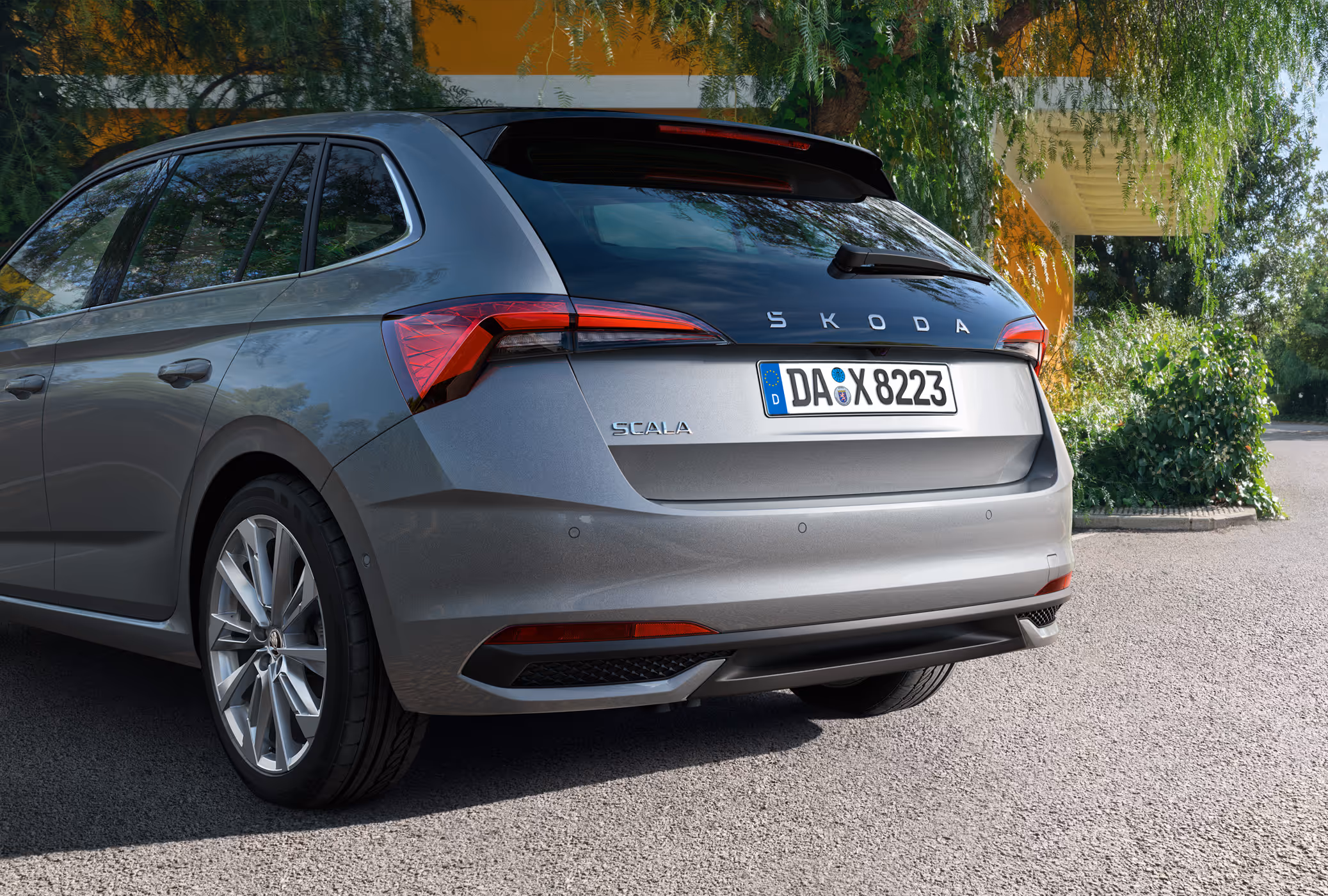 Eine Nahaufnahme zeigt die Heckpartie eines Škoda Scala in der Lackierung Graphite-Grau Metallic. Die Aufnahme hebt das Design der TOP LED-Heckleuchten und die verlängerte, schwarze Heckscheibe mit dem Škoda Schriftzug hervor.