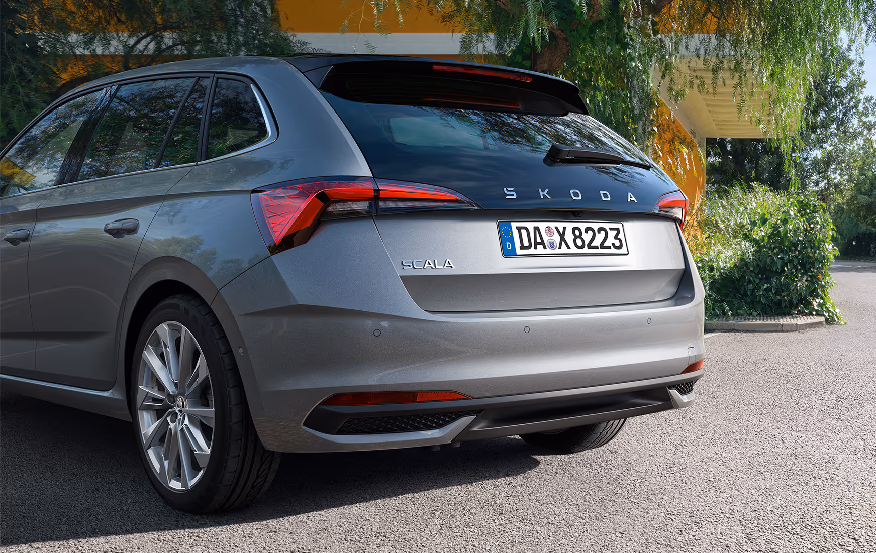 Eine Nahaufnahme zeigt die Heckpartie eines Škoda Scala in der Lackierung Graphite-Grau Metallic. Die Aufnahme hebt das Design der TOP LED-Heckleuchten und die verlängerte, schwarze Heckscheibe mit dem Škoda Schriftzug hervor.