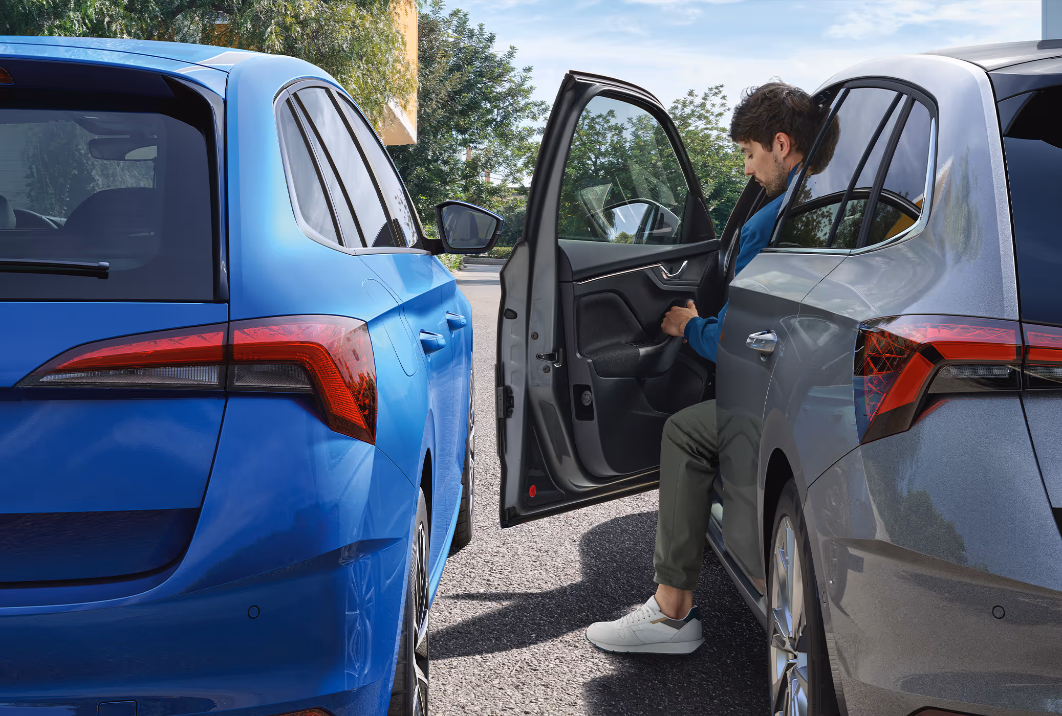 Ein Mann öffnet die Fahrertür eines Škoda Scala, der eng neben einem anderen Fahrzeug geparkt ist. Während des Öffnens fährt der automatische Türkantenschutz aus Kunststoff aus der Türkante heraus.