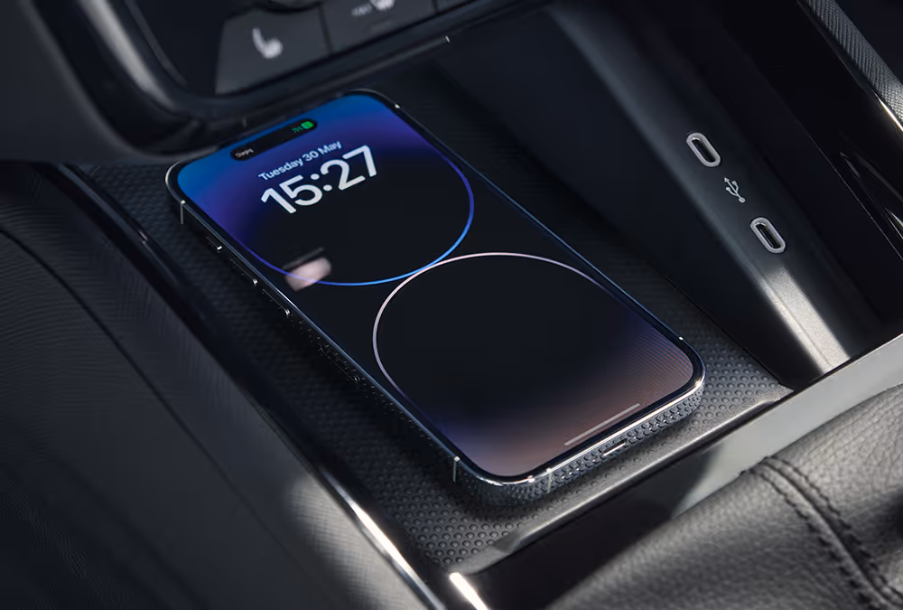 Eine Nahaufnahme zeigt die Phonebox in der Mittelkonsole eines Škoda Scala, in der ein Smartphone kabellos geladen wird. Auf dem Bildschirm des Telefons werden der Ladevorgang und die Uhrzeit angezeigt.