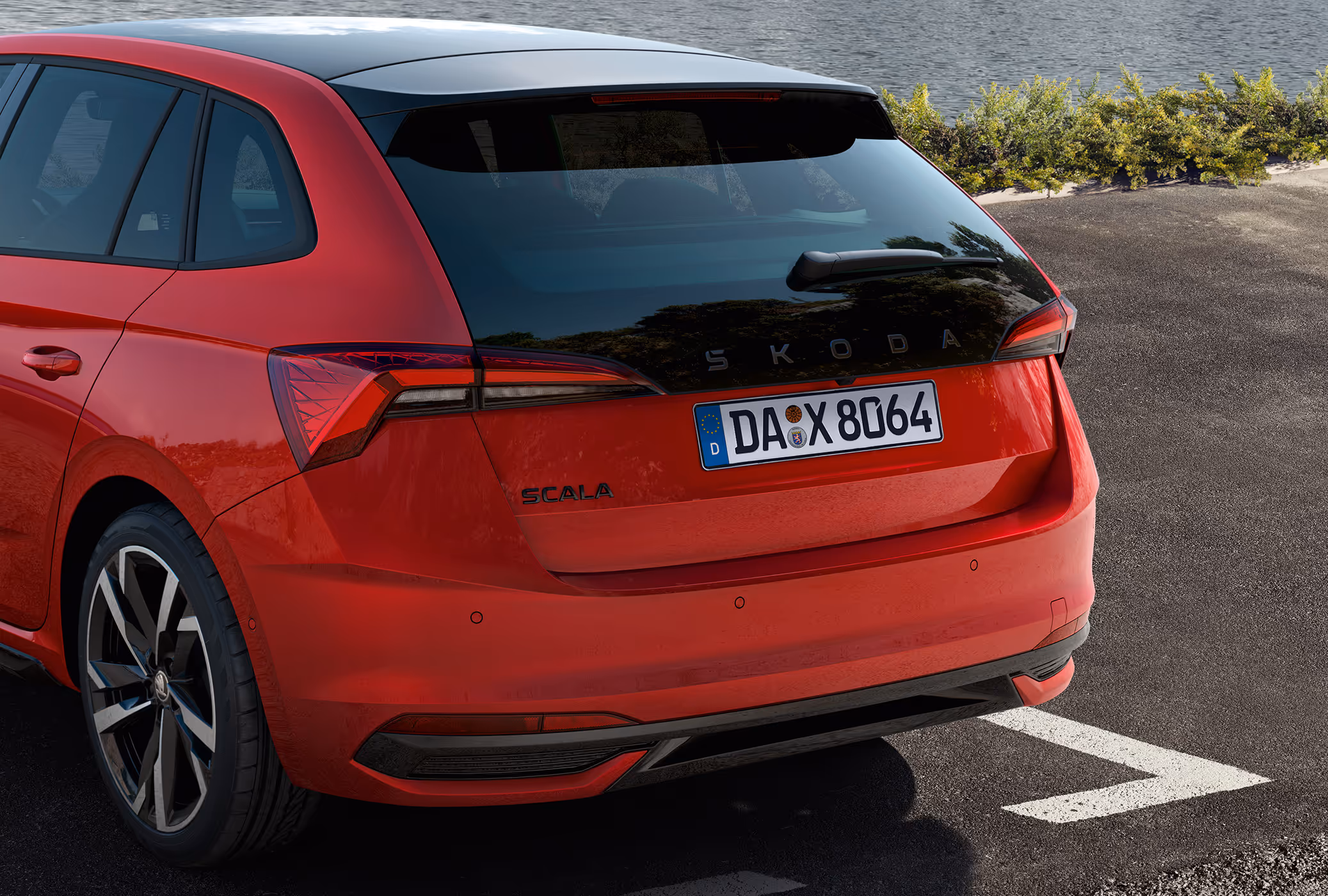 Eine Nahaufnahme zeigt die Heckpartie eines Škoda Scala Monte Carlo in der Lackierung Velvet-Rot Metallic. Die Aufnahme hebt das sportliche Heckdesign mit der verlängerten, schwarzen Heckscheibe, dem schwarzen Škoda Schriftzug und den TOP LED-Heckleuchten hervor.