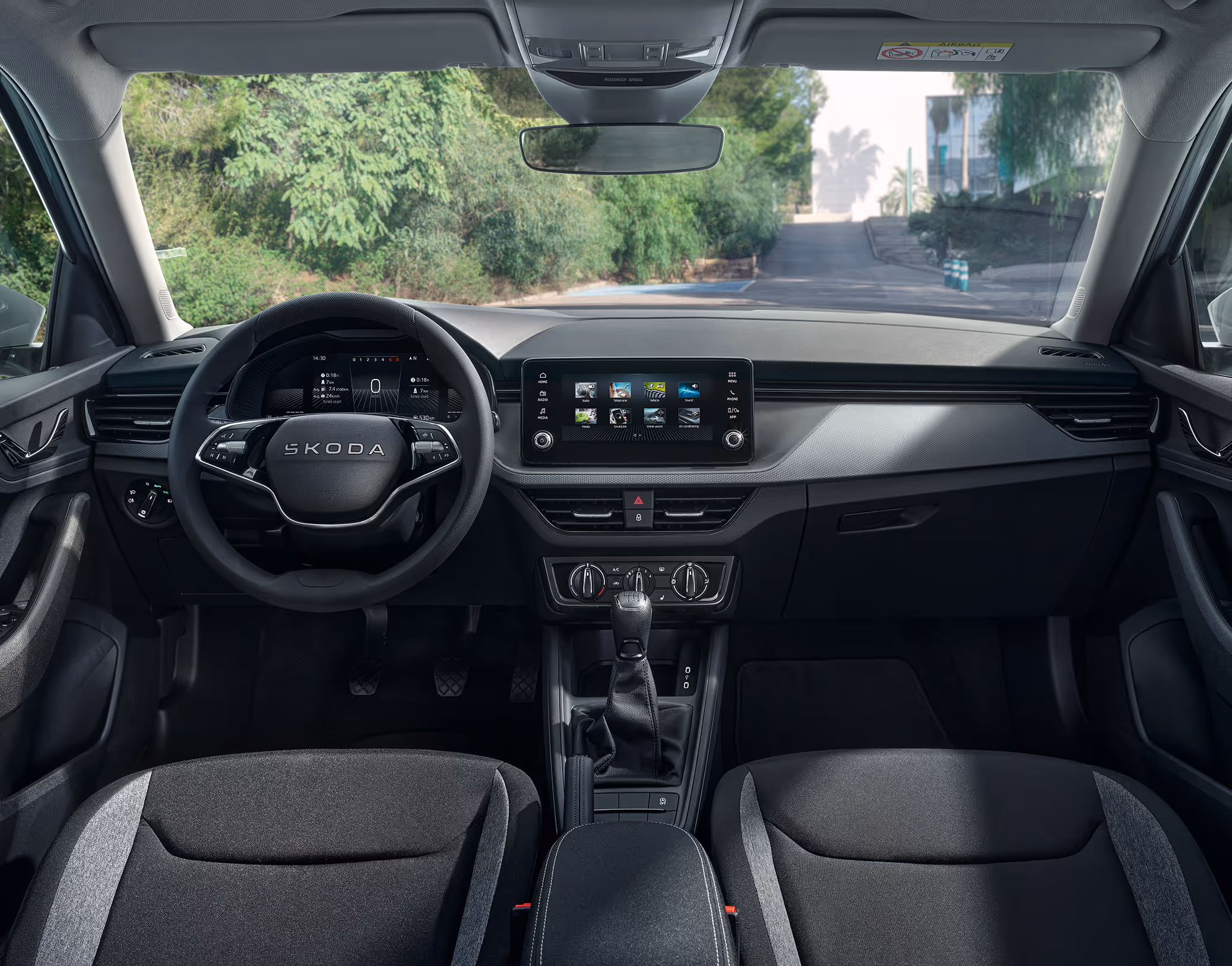Eine weite Innenansicht zeigt das gesamte Cockpit eines Škoda Scala mit der Design Selection Studio. Das Interieur ist mit schwarzen Stoffsitzen und einer schwarzen Dekorleiste am Armaturenbrett ausgestattet.
