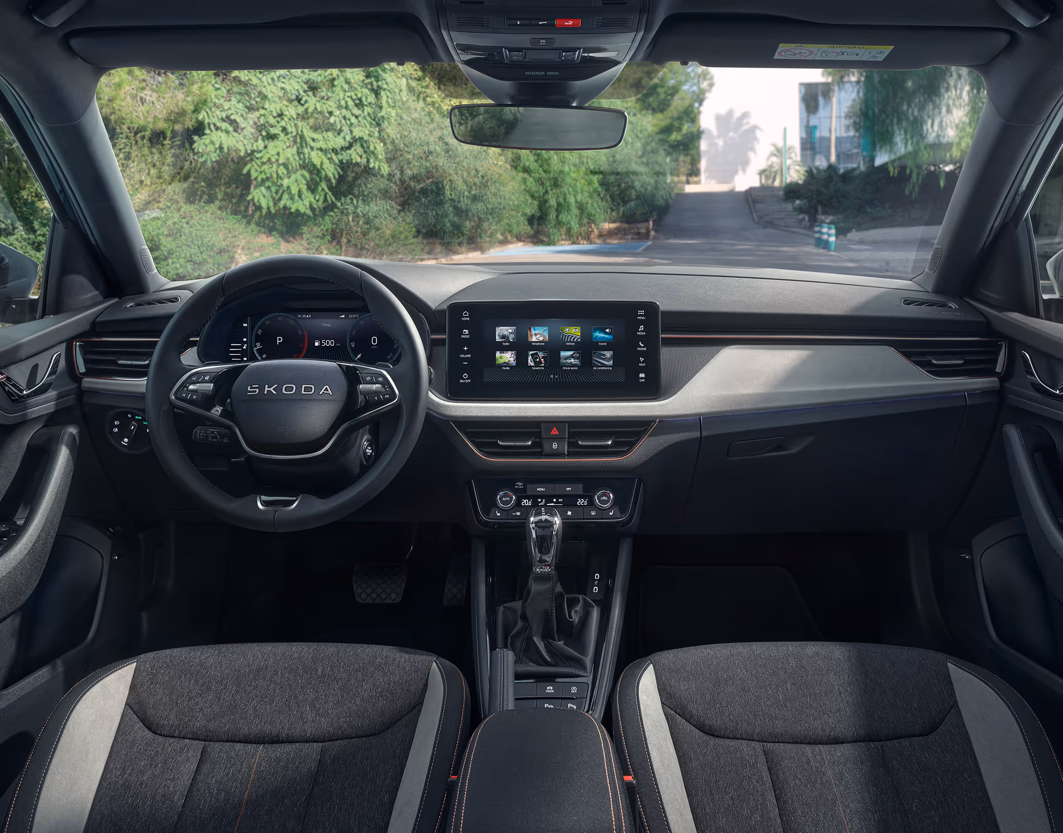 Eine weite Innenansicht zeigt das gesamte Cockpit eines Škoda Scala mit der Design Selection Lodge. Das Interieur ist mit Sitzbezügen in einer Stoff-Suedia-Kombination, die durch kupferfarbene Kontrastnähte akzentuiert werden, und einer Dekorleiste in Kupfer gebürstet ausgestattet.