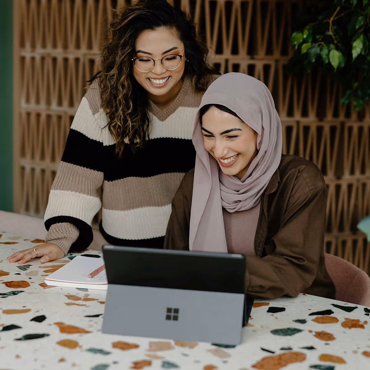 Two women sitting at a table with a laptop.