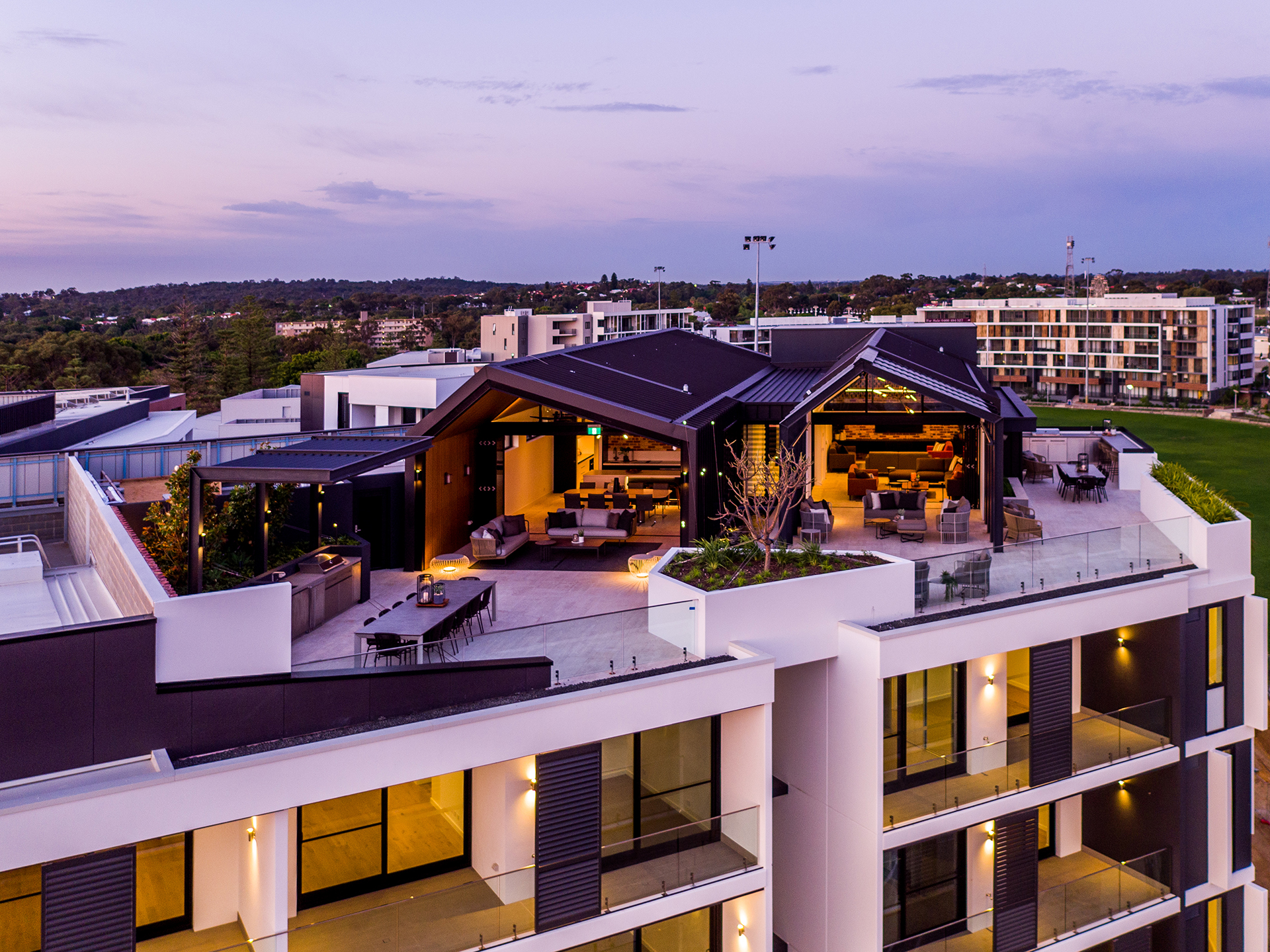 Rooftop view of an outdoor space on a modern building, with cityscape and sky in the background.
