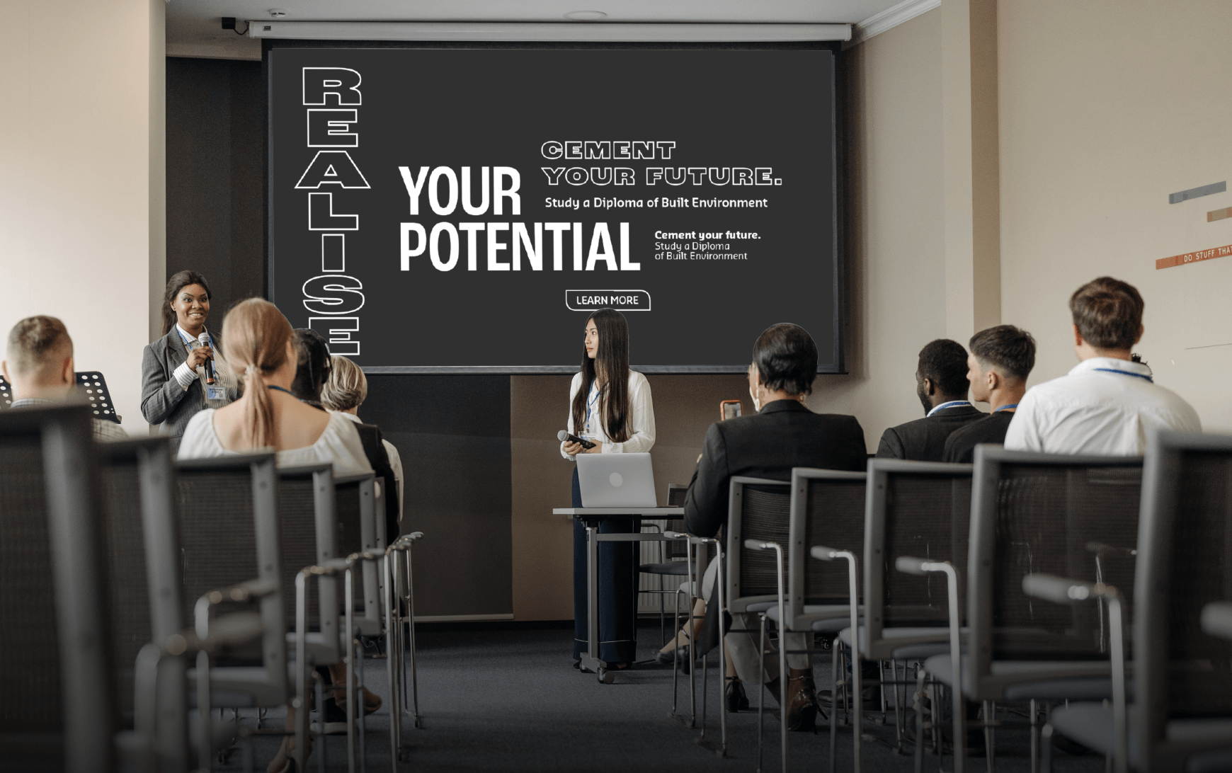 A conference room with a black presentation screen displaying 'Realise Your Potential.'