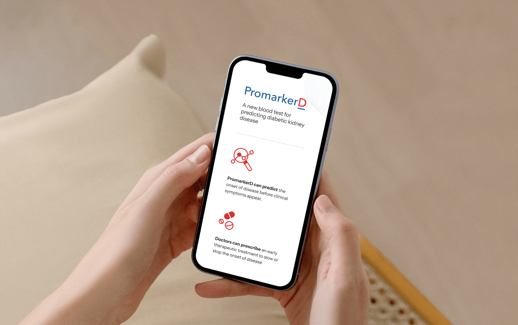 A close up of a hand holding a phone displaying PromakerD on the screen.