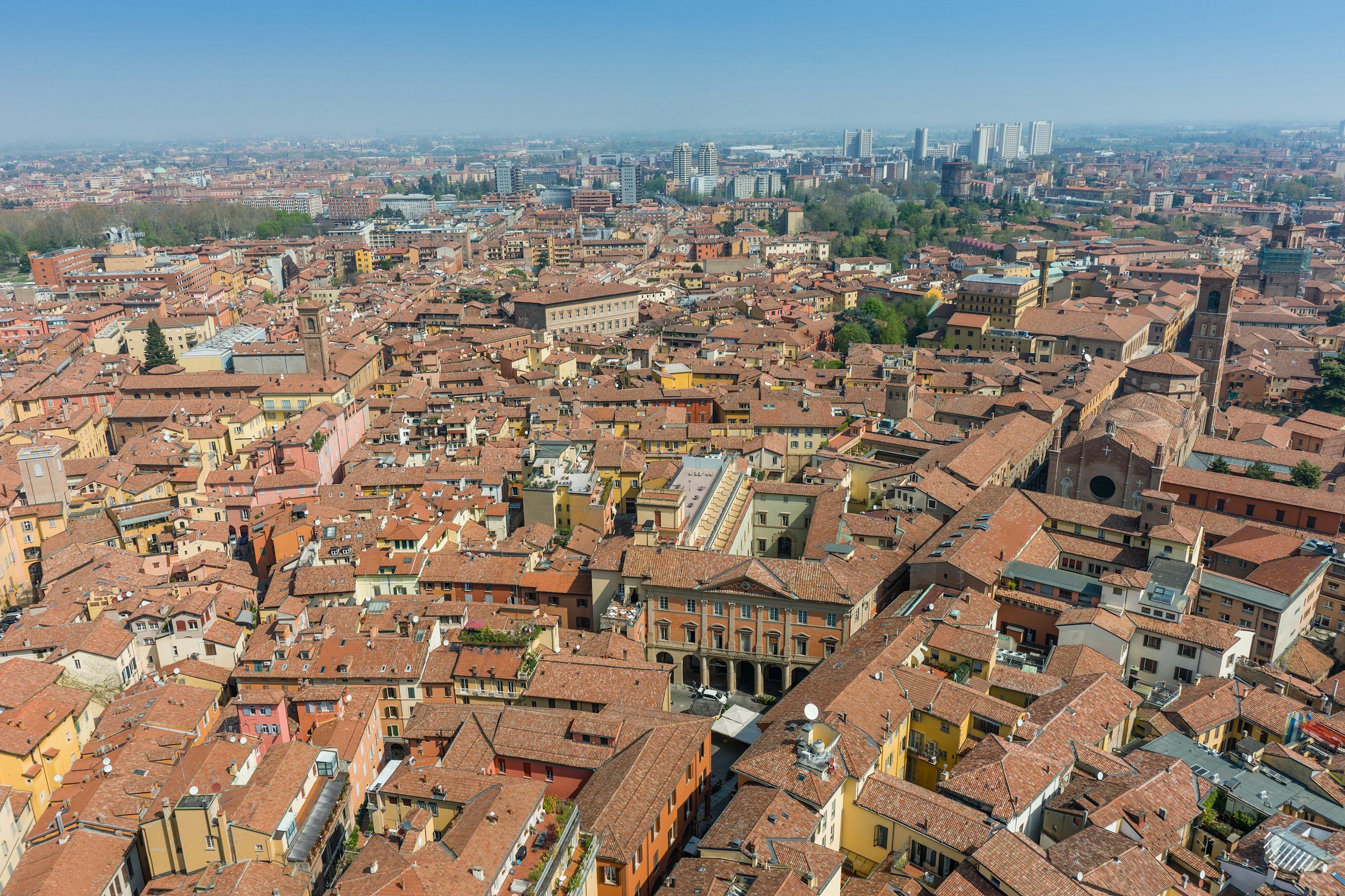 Vista aerea del centro storico di Bologna con i tetti in cotto e, sullo sfondo, i nuovi edifici della città